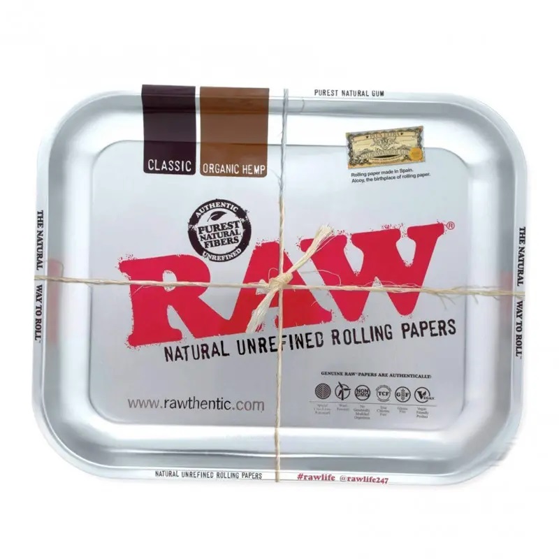 Duża metalowa tacka do skręcania RAW w srebrnym kolorze, z charakterystycznym logo RAW oraz grafiką bletek Classic i Organic Hemp, przewiązana sznurkiem, tacki 